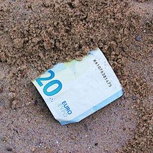 Geldschein unter Sand Foto eines halb von Sand bedeckten Geldscheins